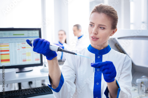 Great job.  Smart concentrated female laboratorian receiving negative results standing in front of the computer and  looking at the medical  appliance  photo