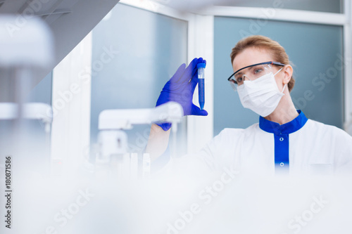 I knew it. Young beautiful  laboratorian examining liquid in test glass while wearing special mask and glasses and standing in the lab photo