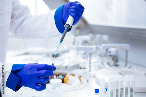 Parental test. Hands in blue gloves holding pipette and test tube with poured blue chemical  which placed on blurred background photo