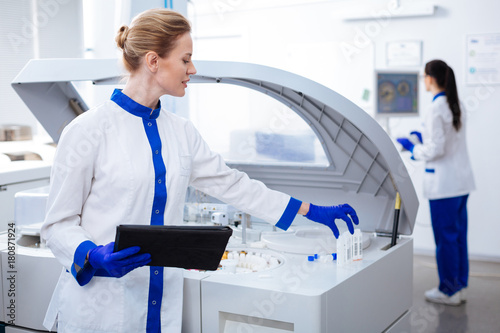 Here we go.  Intelligent genuine female scientist putting glassware according to the list written in the tablet which placed in the hand photo