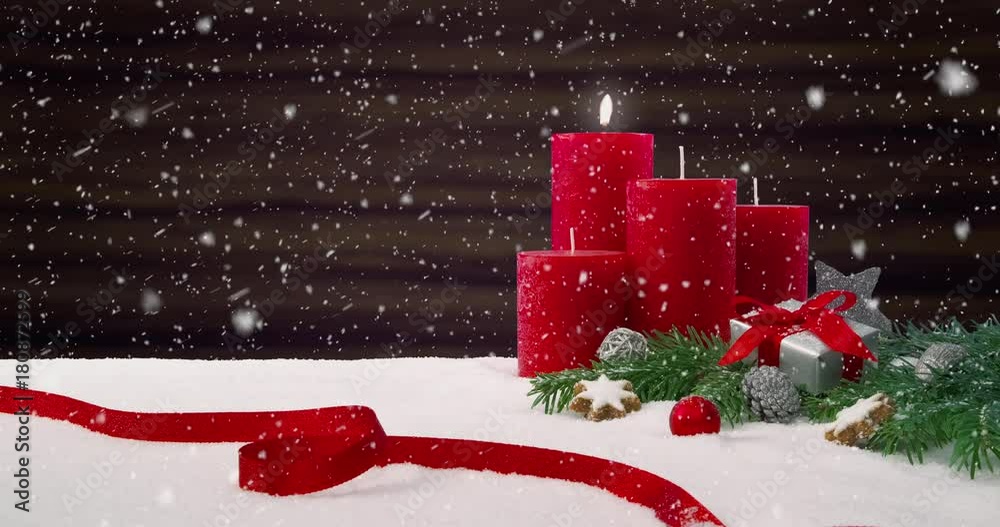 First Sunday of Advent - Beautiful snowfall in front of a Christmas decoration arrangement on a snowy table in front of a wooden background