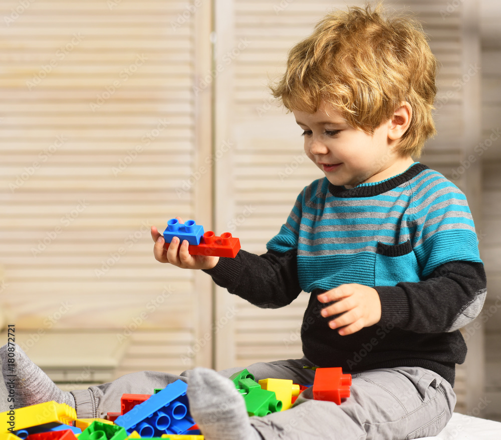 Boy plays with blocks on wooden wall background. Boy plays with blocks on wooden wall background.