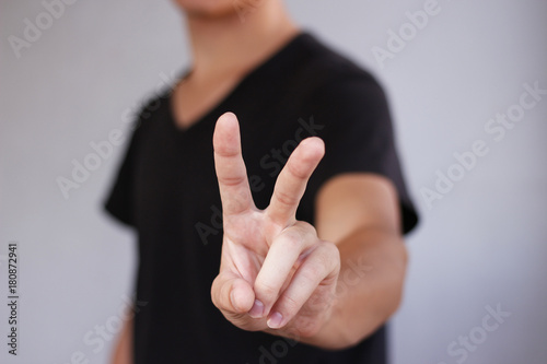 Fototapeta Young man showing two fingers or victory gesture, isolated over white background