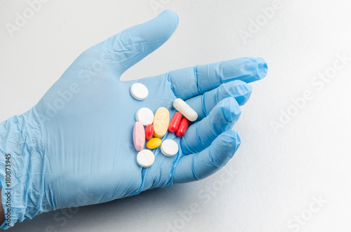 The hand of the medical worker in a medical glove holds pill