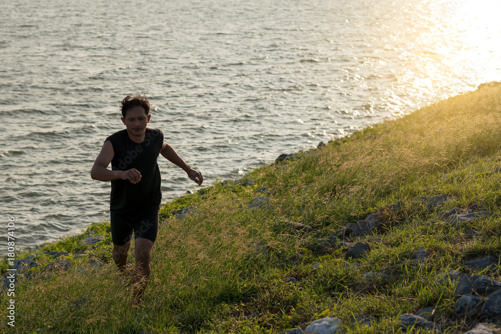 Asia young man running in the nature in the time during sunrise on dam exercise. Healthy lifestyle