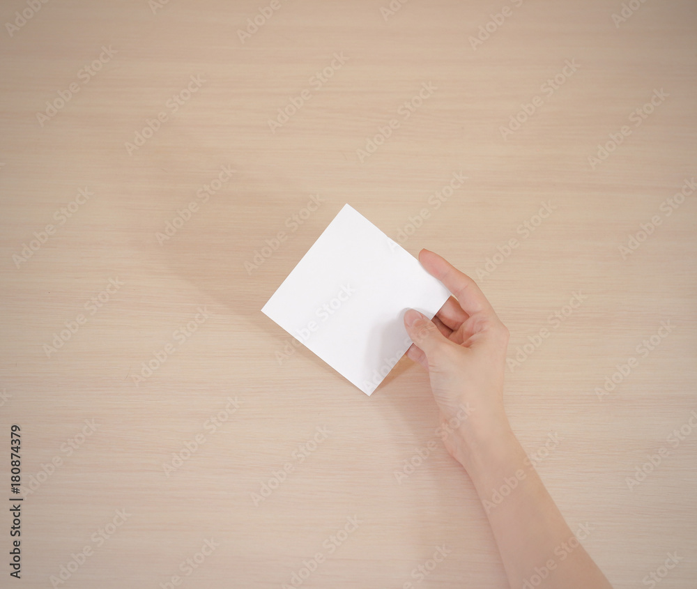 Right hand holding square white paper in the right hand. Leaflet presentation. Right hand holding square white paper in the right hand. Leaflet presentation.
