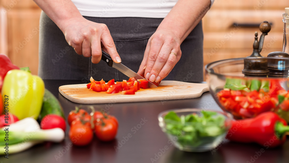 Woman chopping vegetables for a salad - closeup on hands