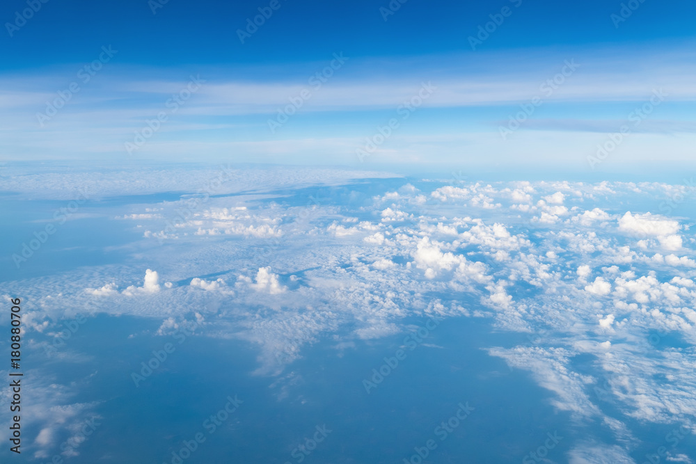 View from airplane window above the clouds with blue sky and cloudscape in sunlight morining. white wispy cirrus and cirrostratus clouds