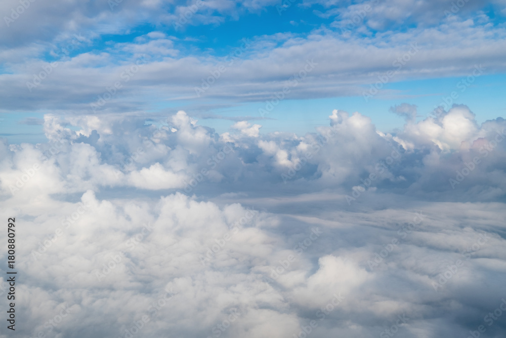 View from airplane window above the clouds with blue sky and cloudscape in sunlight morining. white wispy cirrus and cirrostratus clouds