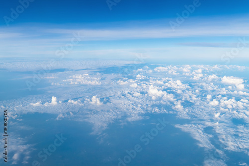 View from airplane window above the clouds with blue sky and cloudscape in sunlight morining. white wispy cirrus and cirrostratus clouds