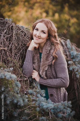 Beautiful genuine lady mystic with curly brunette hairs and adorable eyes dressed in fancy stylish warm clothes with fur on neck lonely posing sit for camera in autumn dark forest photo