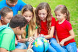 Children with a globe are learning geography at the park