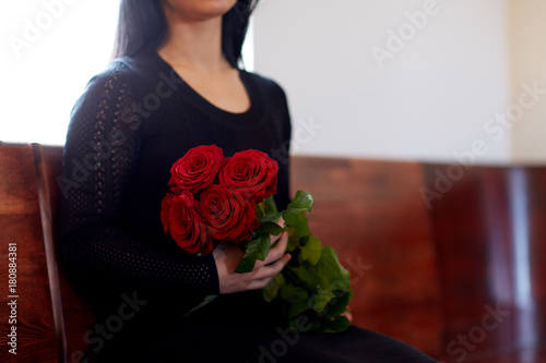 close up of woman with roses at funeral in church