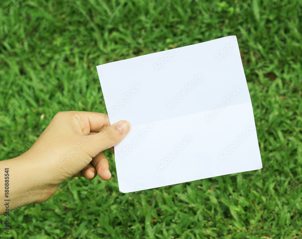 Empty paper sheet in a hand on grass blur nature background. Empty paper sheet in a hand on grass blur nature background.