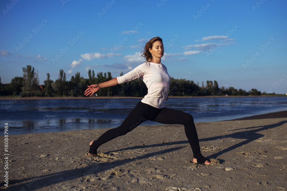 Woman practices yoga and meditates in the open sport position on the beach Woman practices yoga and meditates in the open sport position on the beach