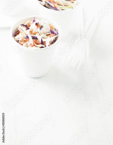 Portions of low-caloric vegetable coleslaw salad in a paper cups.