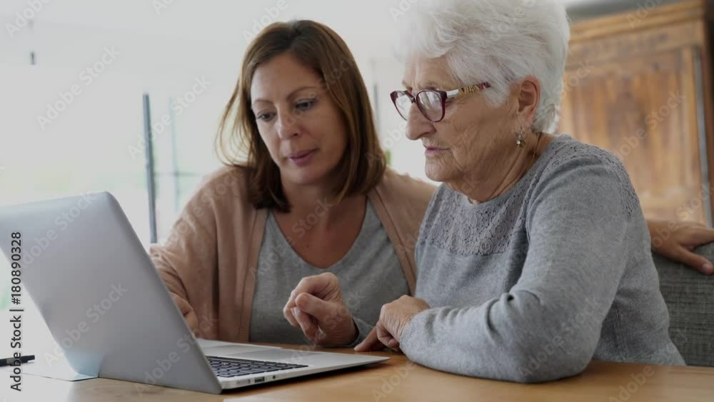 Elderly woman using laptop with help of homecarer Elderly woman using laptop with help of homecarer