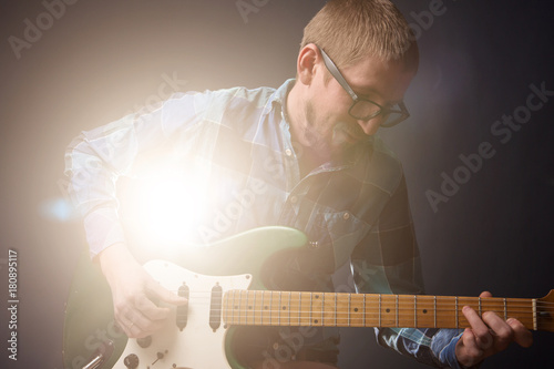 Foto Young guitarist playing on the electric guitar over dark background