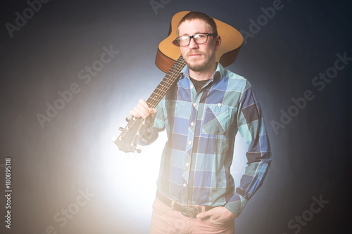 Foto Musican man is standing with guitar in hand on dark background