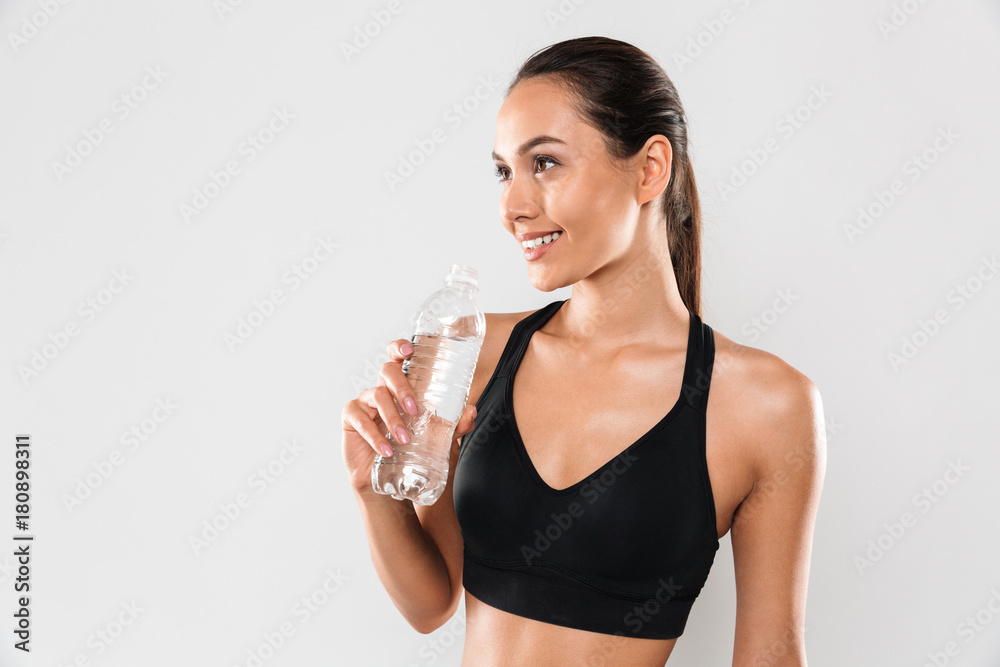 Happy young sports woman posing isolated drinking water.