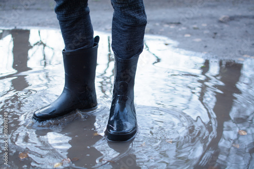 Legs of a man in rubber boots walking on deep puddle