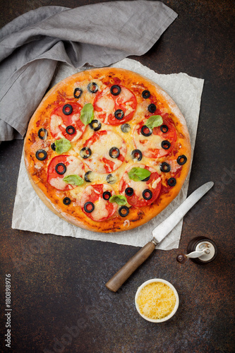 Pizza margarita with tomatoes, mazarella and slices of olives on a dark concrete or stone background. Traditional Italian cuisine. Selective focus. Top view. photo