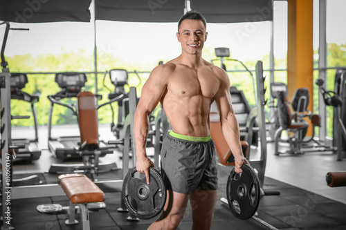 Muscular man with barbell plates in gym