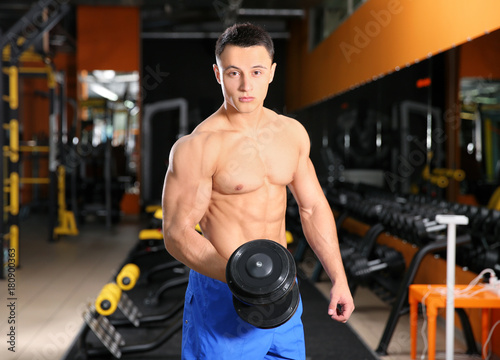 Muscular man training with dumbbell in gym