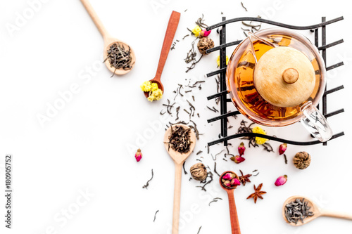 Brew tea with flowers and spices. Dried leaves and petals near tea pot on white background top view copyspace