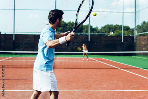 Perfect game together. Rear view of young couple playing tennis on the tennis court © MARIIA
