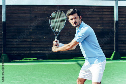 Perfect shot! Young handsome man playing tennis on the tennis court. 