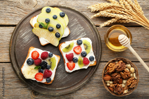 Fototapeta Naklejka Na Ścianę i Meble -  Toasts bread with berries on cutting board with various nuts