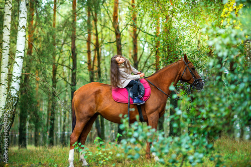 girl teenager rolling on her favorite horse in a beautiful park, best friends.