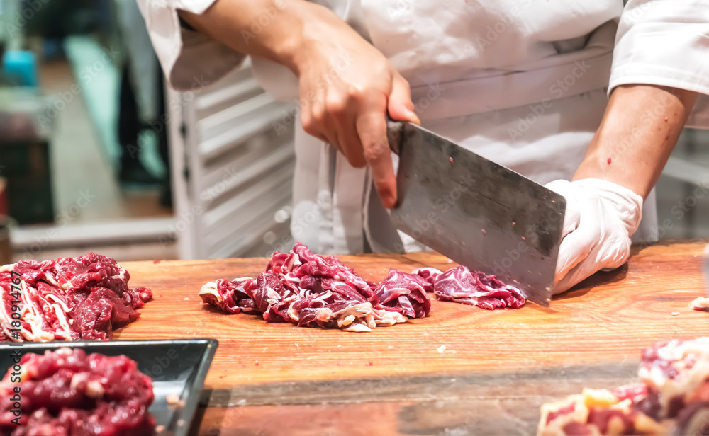 Chef cutting fresh raw meat on wooden board