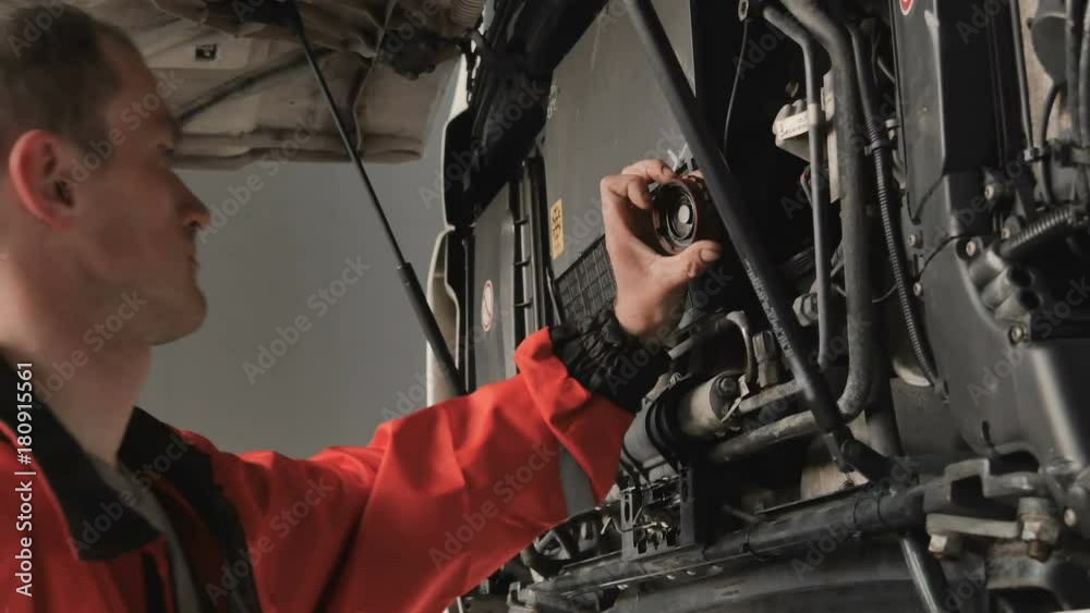 Auto mechanic check something under hood of truck