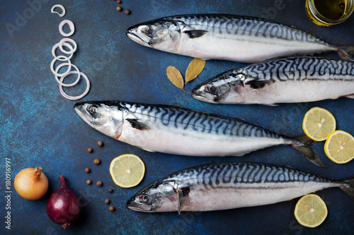 Raw mackerel fish with ingredients for cooking on a blue concrete or stone background. Selective focus. Top view.