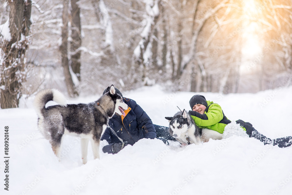 Φωτογραφία The father and son are walking with the husky dogs in the park in the winter