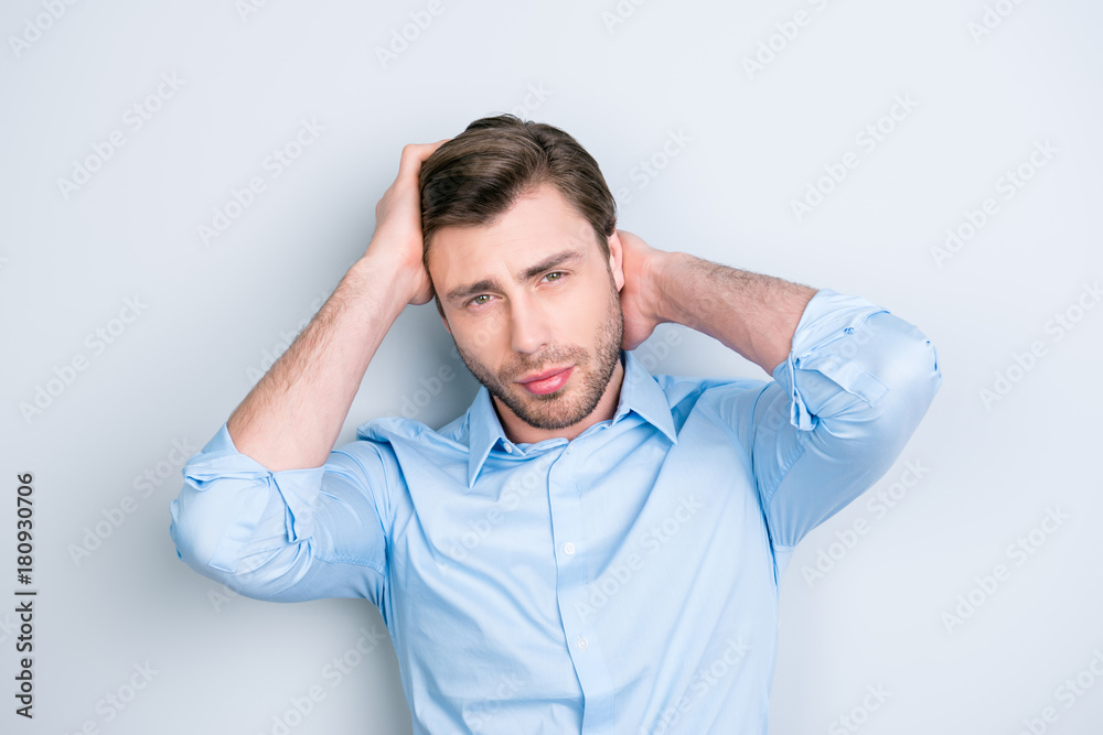 Close up portrait of attractive man touching his perfect hair and looking at camera while standing over grey background Close up portrait of attractive man touching his perfect hair and looking at camera while standing over grey background
