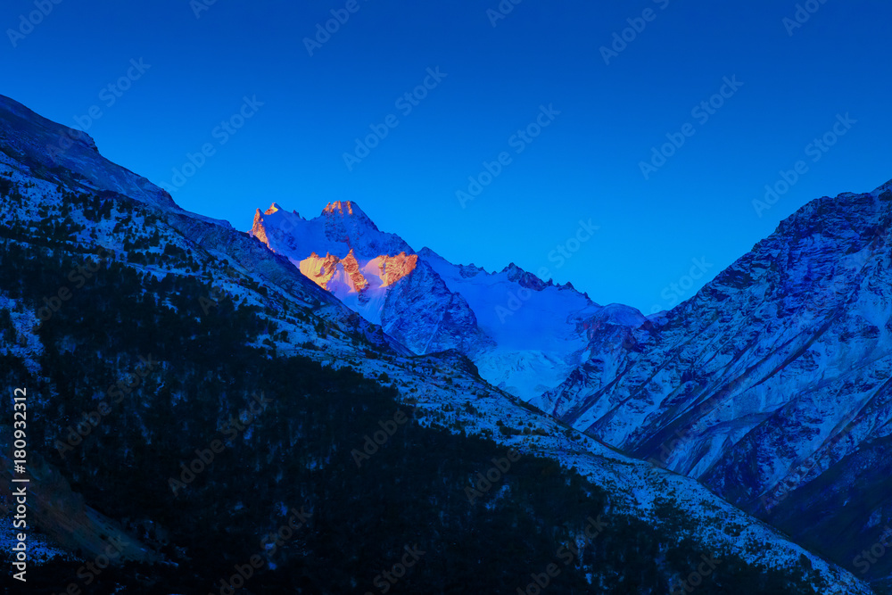 Bright sunset over blue Caucasian mountain peaks in winter morning dusk