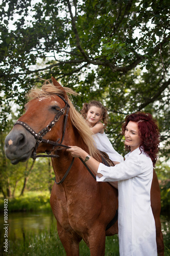 Mother and daughter are riding a horse. Summer meadow.