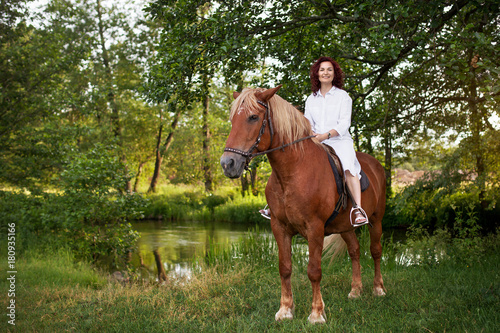 Beautiful woman is riding a horse. Summer meadow.