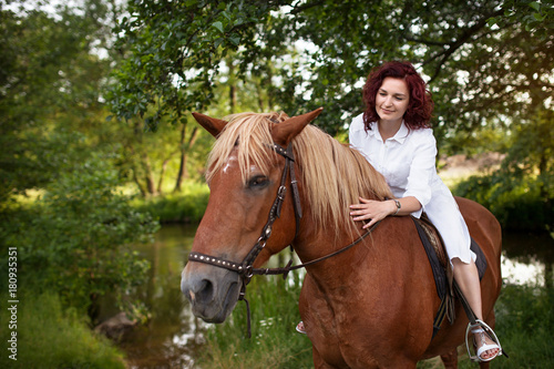 Beautiful woman is riding a horse. Summer meadow. © dinachi