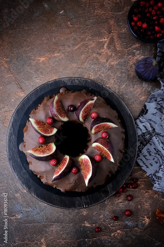 On the stand is a chocolate cake with figs and cranberries