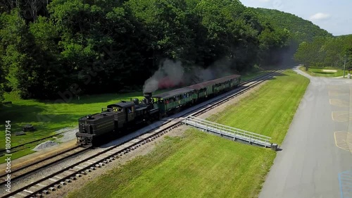 Aerial camera follows a Cass Scenic Railroad train pulls several tourist cars backwards as it moves toward the station with passengers loaded. photo