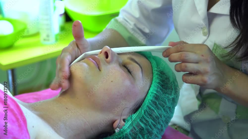 A young girl at a reception with a cosmetologist. The beautician cleanses the face and makes peeling. A young girl at a reception with a cosmetologist. The beautician cleanses the face and makes peeling.