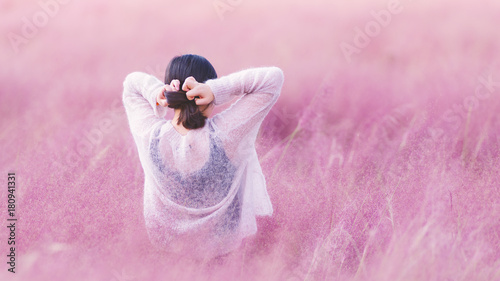 Fototapeta Naklejka Na Ścianę i Meble -  Rear view of beautiful young Chinese woman in white dress standing in the pink hairawn muhly flowers field.