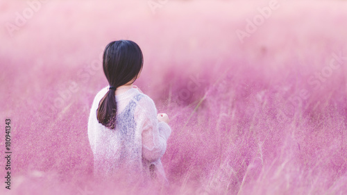 Rear view of beautiful young Chinese woman in white dress standing in the pink hairawn muhly flowers field. photo