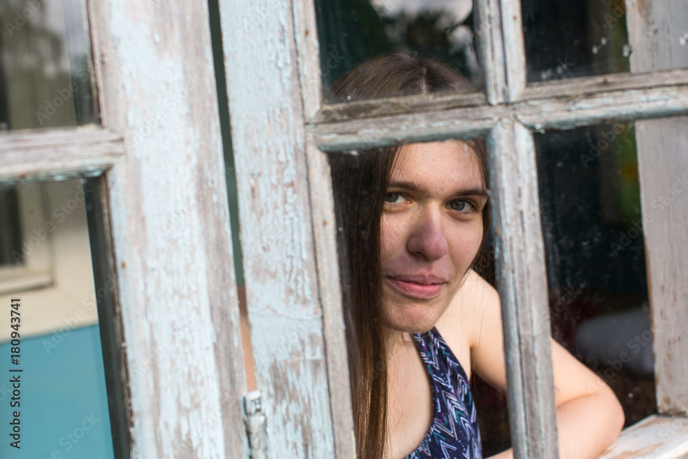 Young woman with long hair looks out of the veranda windows. Young woman with long hair looks out of the veranda windows.