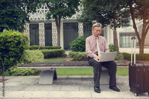asian senior using laptop outdoor