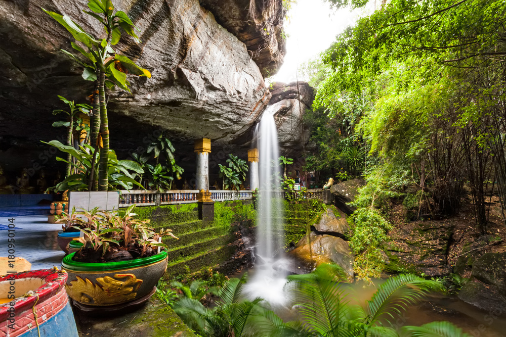 Fototapeta premium Motion blurred water and children play in the temple under waterfall Wat Tham Heo Sin Chai waterfall. Kaeng Tana National Park, Ubonratchathani, Thailand